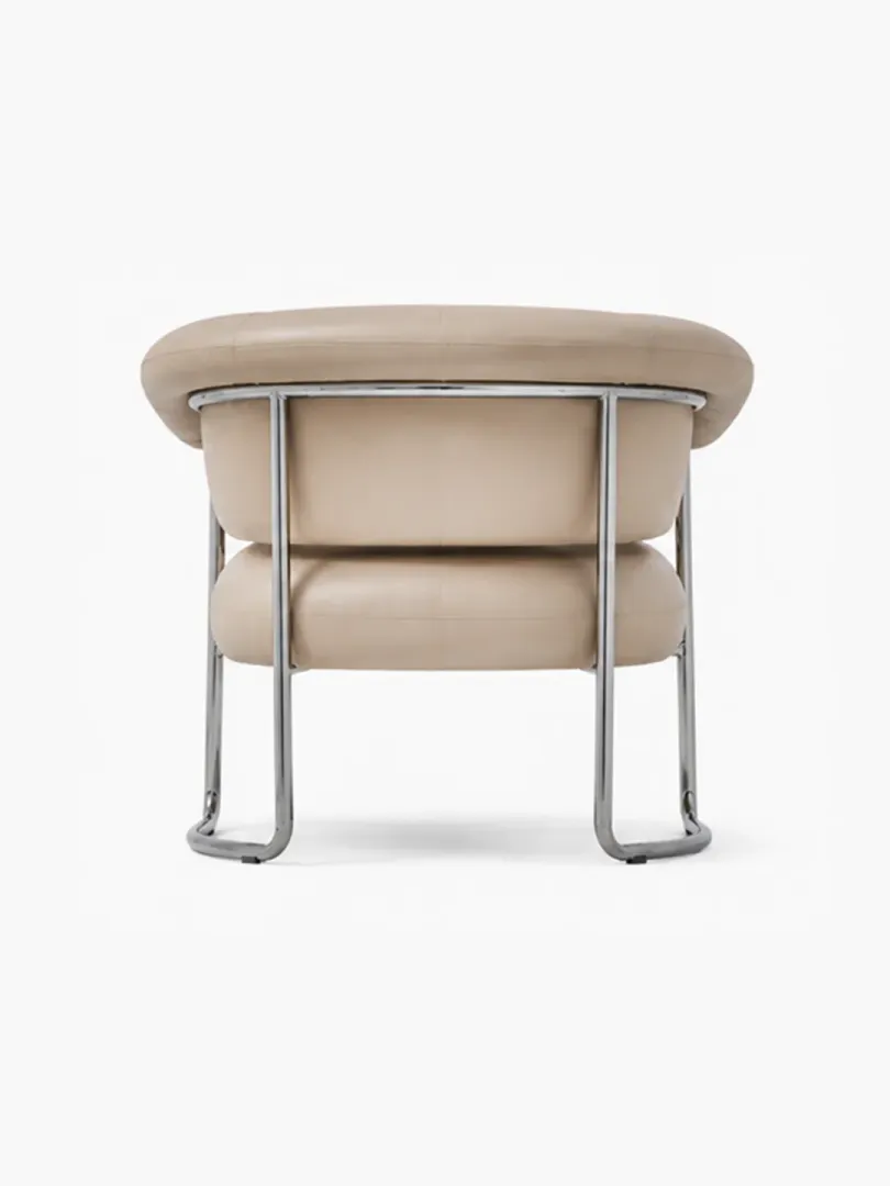 Side view of champagne full grain leather Bauhaus armchair showing tiered cushion construction and polished steel sled base frame